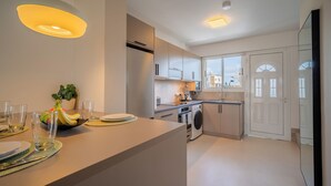 Een moderne keuken met een eethoek, een wasmachine en uitzicht op de stad.