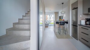 Een moderne keuken met een roestvrijstalen koelkast, een eethoek met een tafel en stoelen, en een trap die naar een ander niveau leidt.