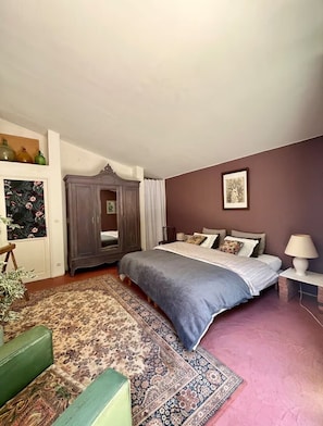 A bedroom with a bed, a dresser, a mirror, a rug, and a lamp.