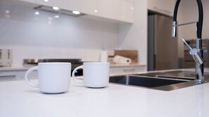 Una cocina moderna con armarios blancos, electrodomésticos de acero inoxidable y un grifo negro.