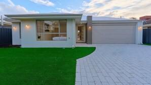 Una casa moderna con garaje, un porche cubierto y un césped cuidado.