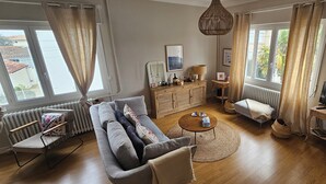 A living room with a sofa, a coffee table, a TV stand, and a radiator. - Entire villa - Entre Chay & Pontaillac in Royan (Royan)