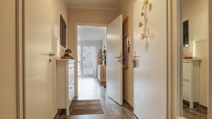A hallway with a wooden floor, white walls, and a door leading to a room. - Ankerplatz-Neumarkt - My vacation apartment in the heart of Bremerhaven! (Bremerhaven)