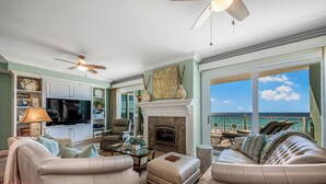 A spacious living room with a fireplace, comfortable seating, a television, and a view of the ocean. - Luxury Gulf-Front Escape at En Soleil, Two King Suites & Stunning Views (Panama City)