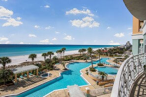 Ett poolområde på ett semesterhotell med flera pooler, palmer och utsikt över stranden.