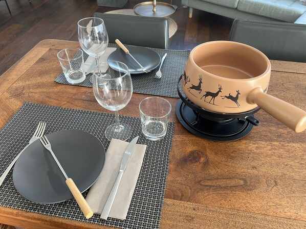 A dining table set with plates, cutlery, glasses, and a decorative pot. - 3.5 room apartment "Casa Pluschein" with a dream view in a prime location in Flims (Flims Waldhaus)