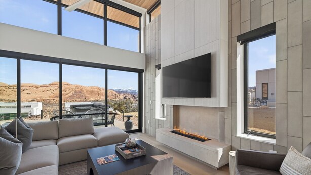Una sala de estar moderna con un televisor grande, una chimenea y vistas a un paisaje desértico.