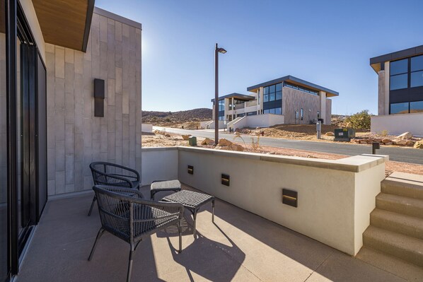 Eine moderne Terrassenausstattung mit Korbmöbeln und einem Betonpflanzgefäß.