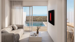 Ein modernes Wohnzimmer mit großem Fenster mit Blick auf einen Pool und eine Steinwand, einem an der Wand befestigten Flachbildfernseher und einem minimalistischen Couchtisch.