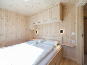 A wooden-paneled room with a bed, built-in cabinets, and wall-mounted lighting. - NEW! Cosy comfortable newly built wooden house with fantastic view (Vradal (Telemark))