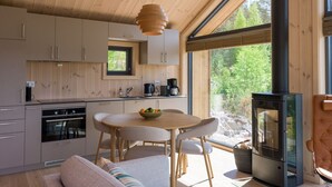 Eine moderne Küche mit Holzausstattung, einem Esstisch und einem Kaminofen.