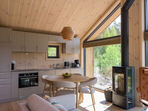 Eine moderne Küche mit Holzausstattung, einem Esstisch und einem Kaminofen.
