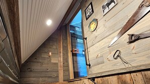 Un escalier en bois avec des rampes en métal, un mur en bois au décor rustique et une fenêtre donnant sur l’extérieur.
