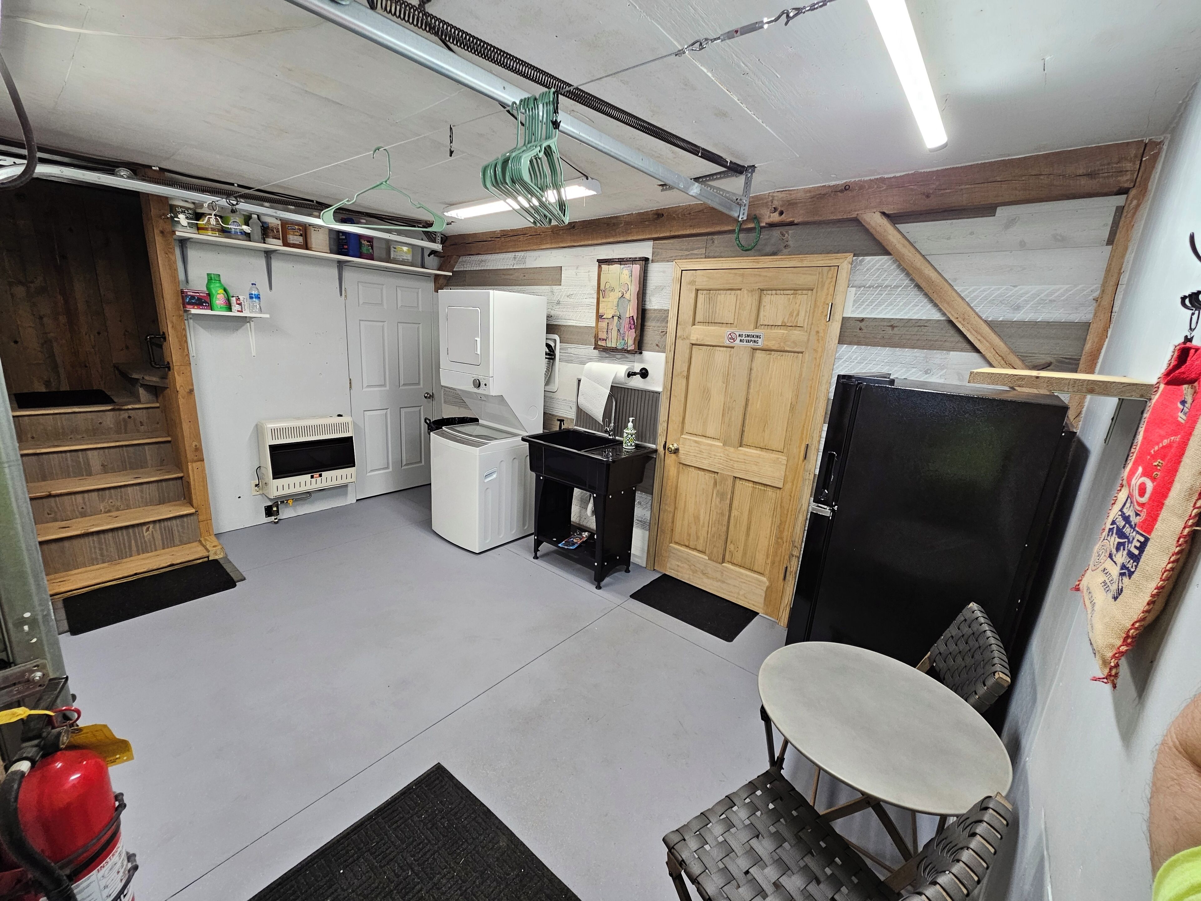A compact kitchen with a washing machine, a refrigerator, and a wooden door with a "No Smoking" sign.
