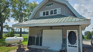 Un petit bâtiment orné d’un logo représentant un alligator, avec une porte de garage blanche et un banc en bois à l’extérieur.