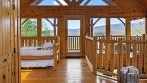 Une cabane en bois avec un lit, une fenêtre et un balcon.