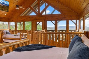 A wooden cabin with a bed, a bench, and a view of the mountains. - *NEW SAUNA* Mountain Views • Game Room • Hot Tub (Sevierville)
