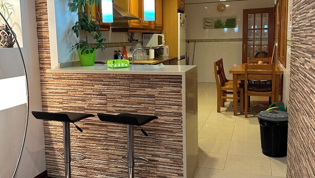 Une cuisine moderne avec des meubles en bois, un four à micro-ondes et un coin repas comprenant une table et des chaises.