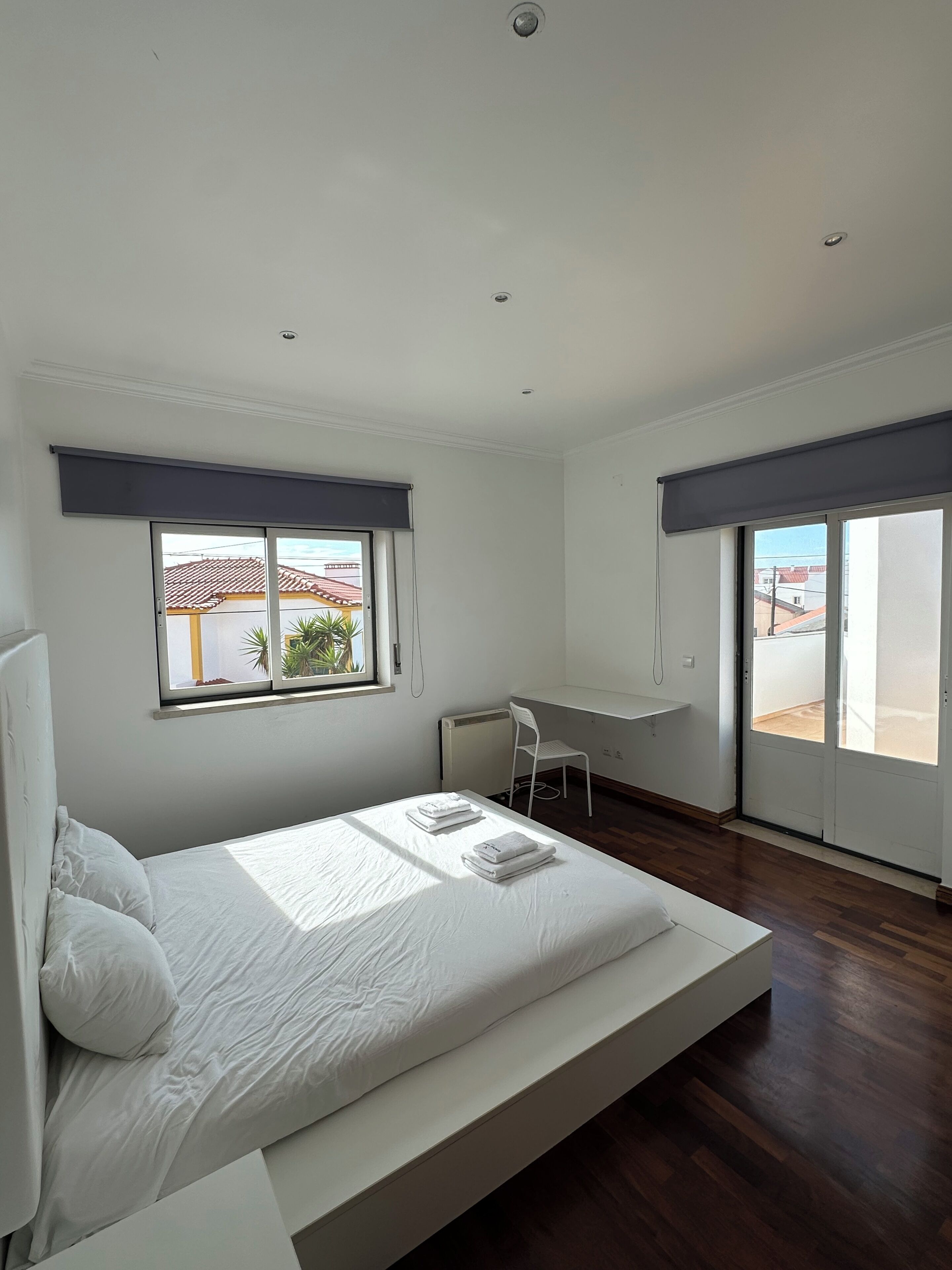 A modern bedroom with a bed, a desk, and a view of the outside.