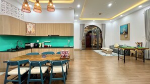 A modern kitchen with a dining area, wooden cabinets, and a green countertop.