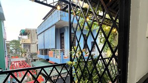 A balcony with a view of a blue building, a wooden floor, and a metal railing. - ConiHouse III Thong Dong (Hue)