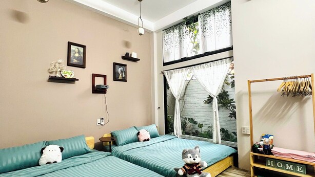 A modern bedroom with a large bed, a small table, and a window with curtains. - ConiHouse III Thong Dong (Hue)