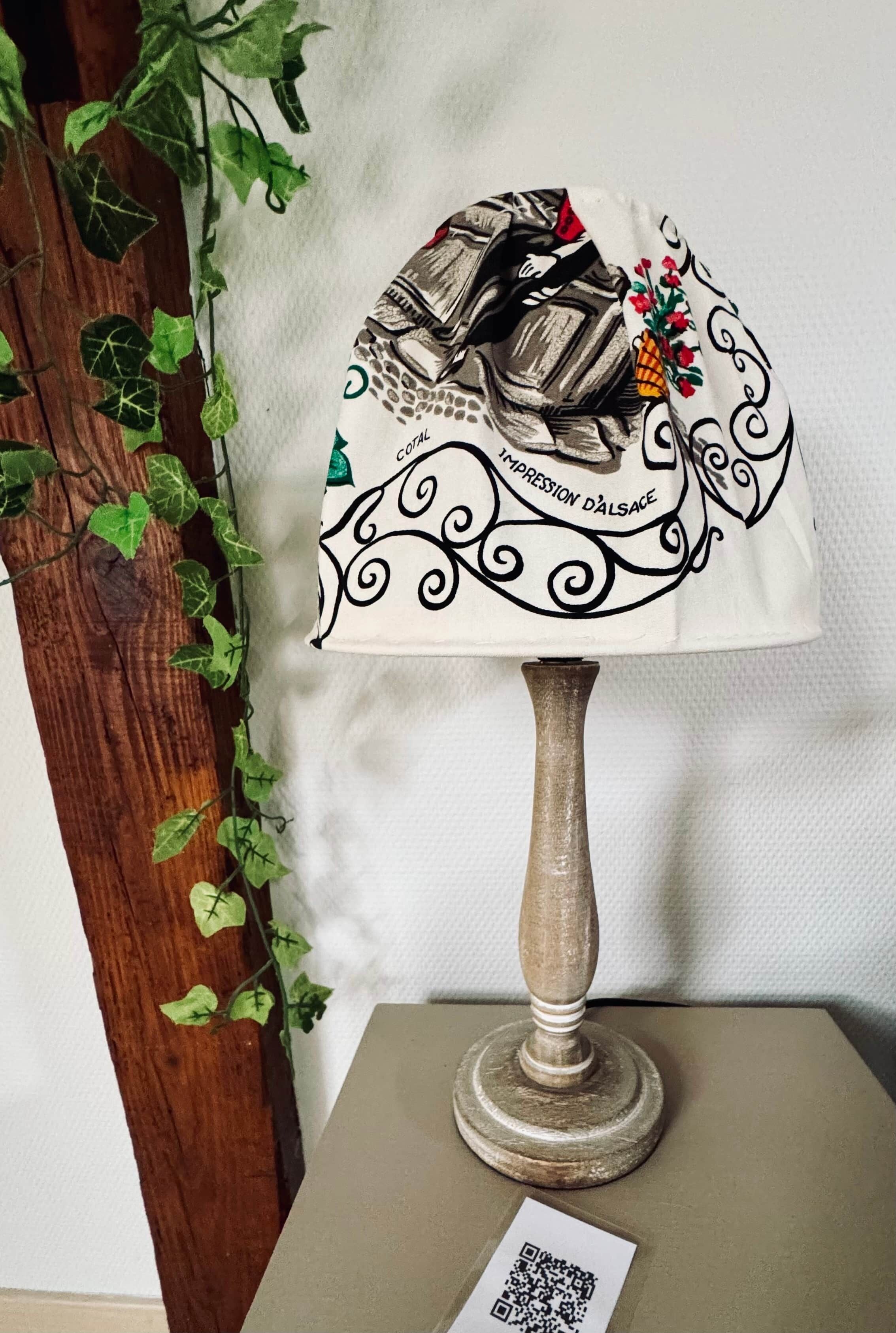 A lamp with a decorative lampshade featuring a floral pattern and the text 'CULTURAL IMPRESSION D'ALSACE.'