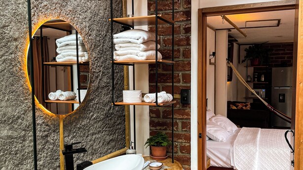 A modern bathroom with a wooden vanity, a large mirror, and a built-in shelf for towels. - Artisanal Amazonian Suite, A Natural Refuge in Puyo (Puyo)