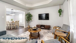 A modern living room with a dining area, a flat-screen TV, and a large plant. - Cozy & Quiet - CENTRAL Location - Master’s Retreat! (Augusta)