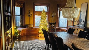 A dining area with a wooden table, chairs, a patterned rug, a chandelier, and a Christmas tree. - Quaint 7 bedroom mansion in charming Dubuque perfect for families (Dubuque)