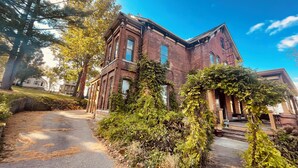 A large, historic brick building with a prominent entrance and a well-maintained garden area. - Quaint 7 bedroom mansion in charming Dubuque perfect for families (Dubuque)