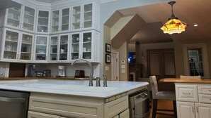 A kitchen with white cabinetry, a central island, and a hanging light fixture. - Quaint 7 bedroom mansion in charming Dubuque perfect for families (Dubuque)