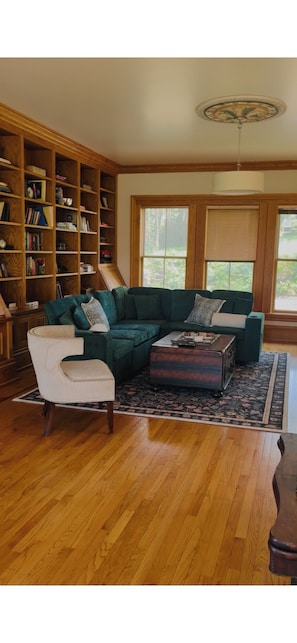 A living room with a sectional sofa, a side chair, a wooden coffee table, and a bookshelf. - Quaint 6-bedroom mansion in charming Dubuque perfect for families (Dubuque)