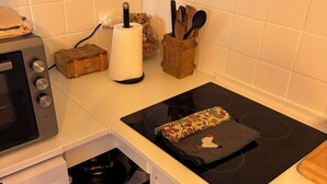 Een kleine keuken met een fornuis, oven en een kleine koelkast.