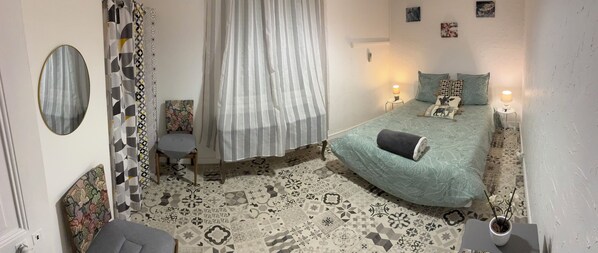 Une chambre à coucher avec un lit, des tables de chevet, une chaise, un miroir et un sol à motifs.