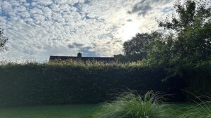 A grassy area with a hedge and a building in the background. - Vacation Rental with a Garden—Right Next to a Riding/Children's Farm (Attendorn)