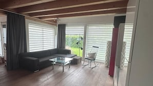 A living room with a sofa, coffee table, and a rocking chair. - Vacation Rental with a Garden—Right Next to a Riding/Children's Farm (Attendorn)