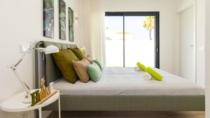 A modern bedroom with a bed, pillows, a bedside table, and artwork on the wall. - Villa with heatable pool near the Marina (Quarteira)