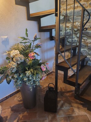 A staircase with stone walls and a potted plant with various flowers.