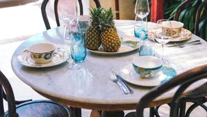 Ein runder Tisch mit zwei Ananas, einer Schüssel und einer Tasse.