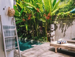 Terraza de madera con una silla de descanso y una piscina pequeña.