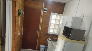 Una cucina compatta con forno a microonde, fornello e una piccola finestra. Un tavolo da pranzo con tovaglioli a quadri blu e sedie è sistemato al centro.