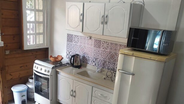 Una cucina compatta con mobili bianchi, un fornello, un forno a microonde e un frigorifero.