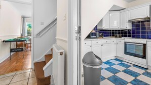 Una cocina moderna con armarios blancos, piso con azulejos azules y blancos, y horno empotrado.