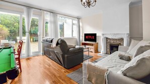 Una sala de estar con sofá, televisión mostrando 'NETFLIX', chimenea y mesa de billar.