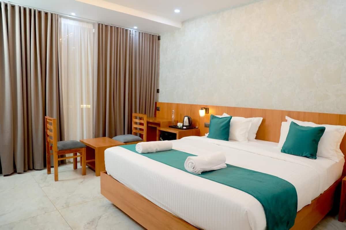 A hotel room with a large bed, a desk, and a chair.
