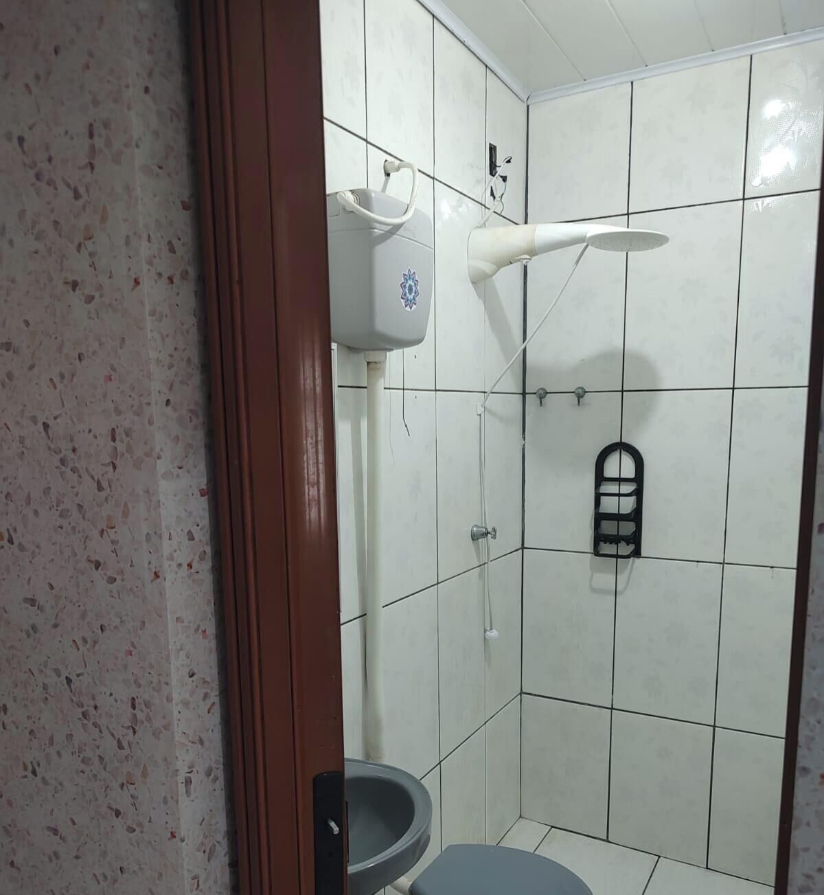 A small, tiled bathroom with a toilet, a shower, and a hand dryer.