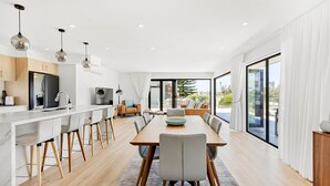 Uma cozinha moderna com ilha central, banquetas e iluminação pendente.