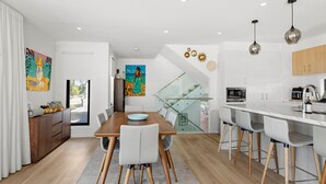 Cozinha moderna com área de refeições, escada e vista para o exterior.