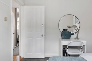 A bedroom with a white door, a bedside table with a lamp, a chair, and a bed. - Bell Street NW1, Edgware Rd, Marylebone (London)